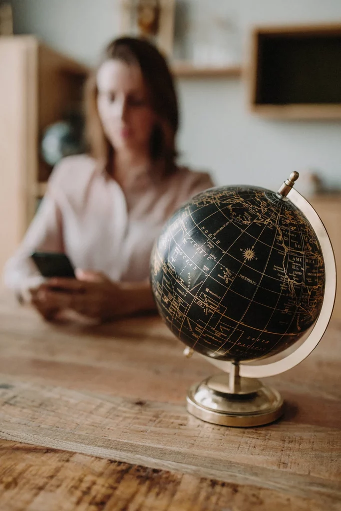 Globe on a desk while Bianca checks her phone — managing stress as a professional