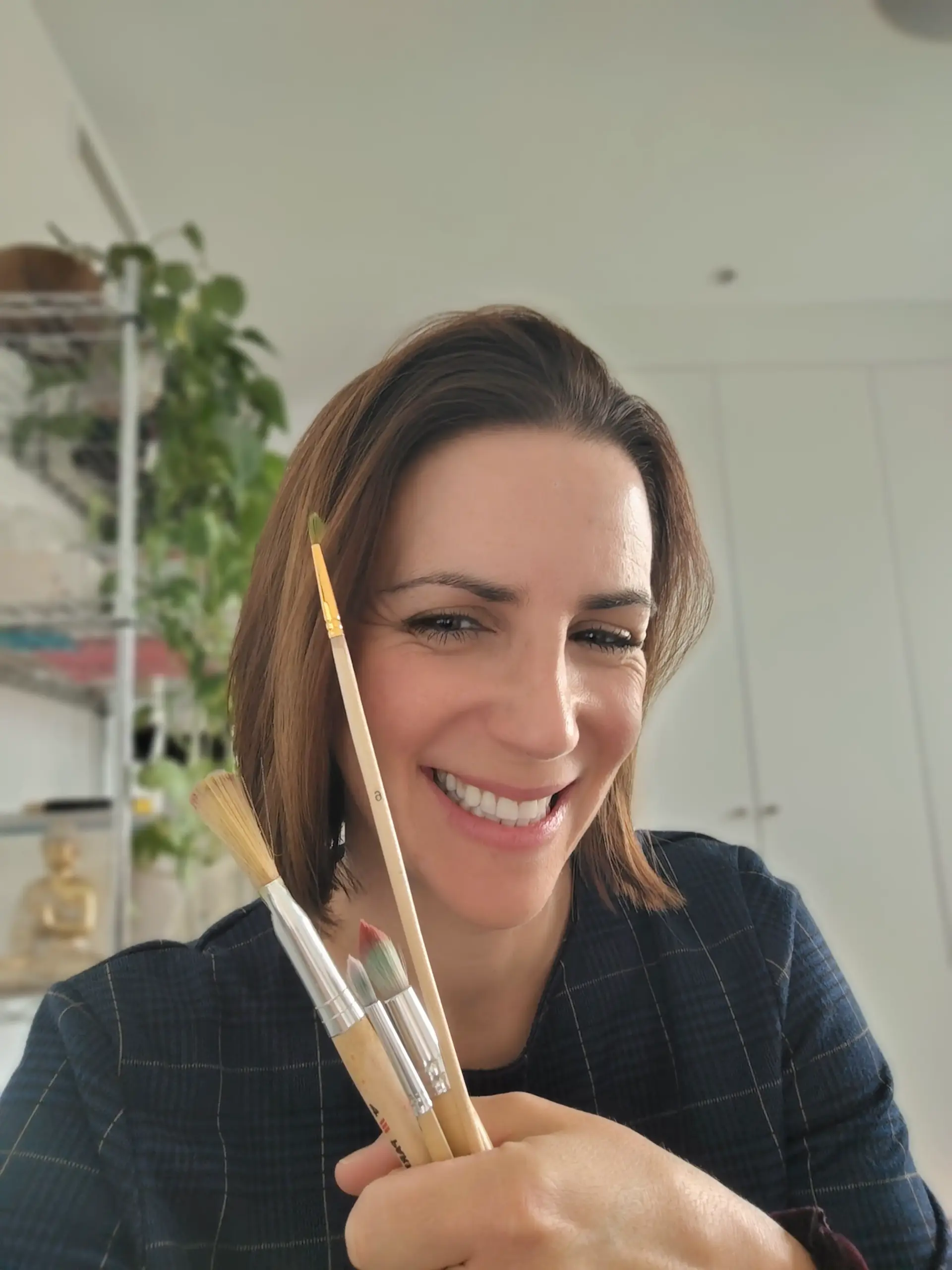 Bianca Topham smiling with paintbrushes during an art for wellbeing coaching session